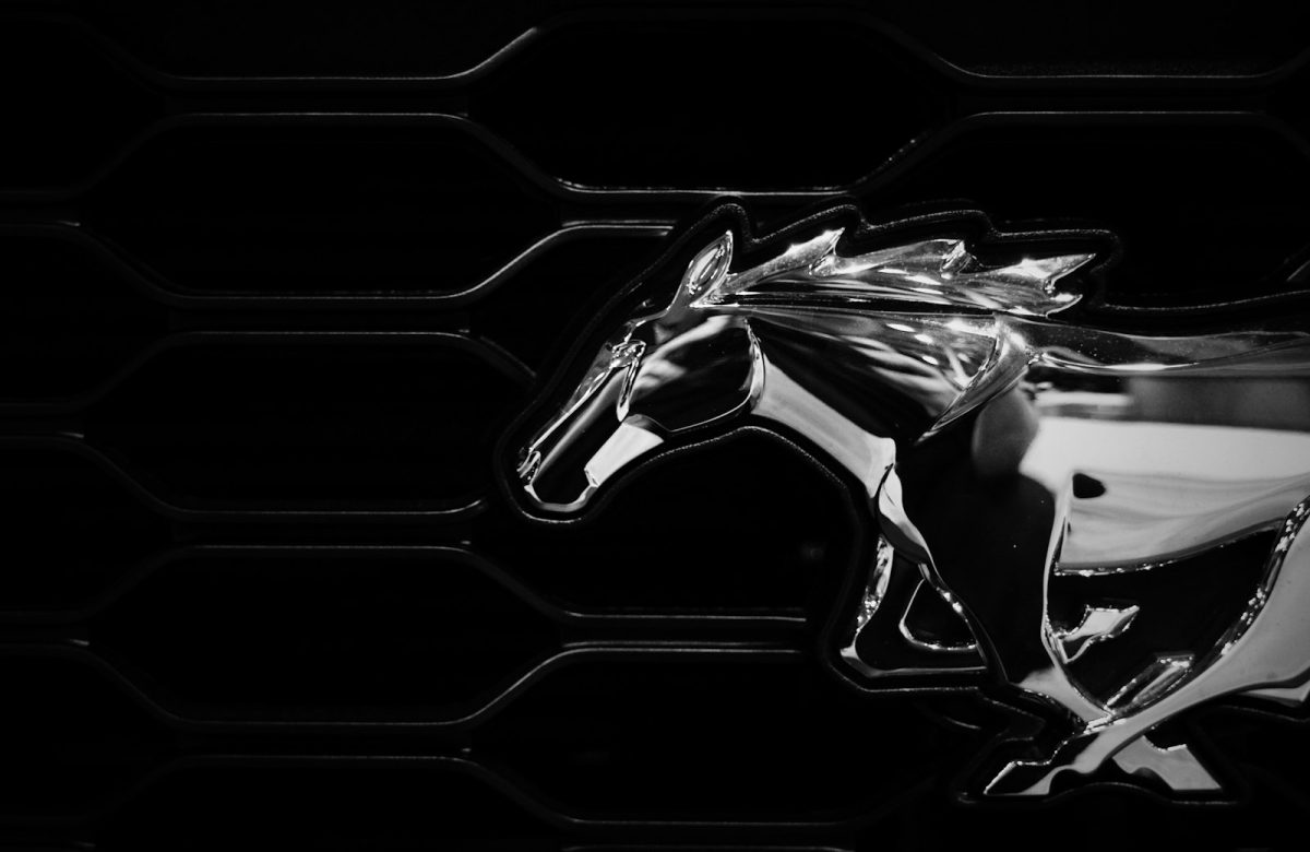 Chrome running horse emblem on a black grille, one of the famous car logos