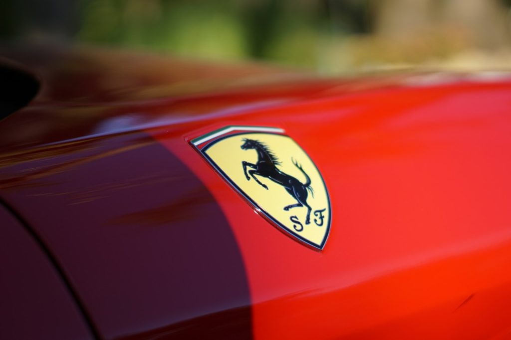 Escudo del logo de Ferrari con el caballo negro sobre la carrocería roja de un deportivo