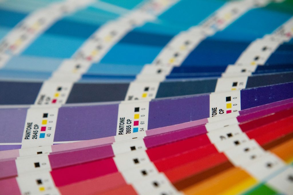 RGB vs CMYK color swatch guide with printed ink samples spread on a table